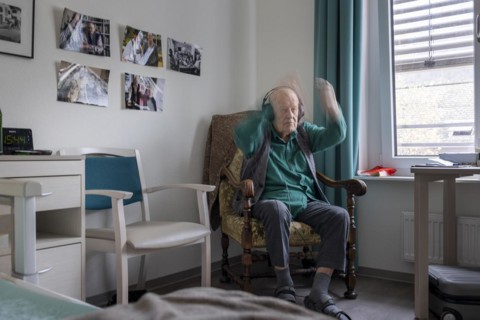 Old man in nursing home conducts to music