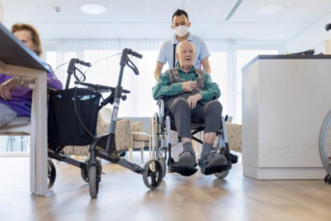 Carer with man in wheelchair in nursing home