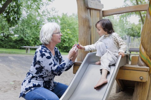 Volunteer. Temporary grandmother with a child in the playground.