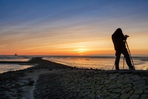 Tourist with camera during sunset on the Trischendamm