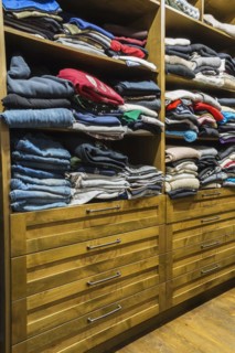 Antique finished chest of drawers with integrated shelves and exposed assorted clothes in walk-in closet in main bedroom inside home