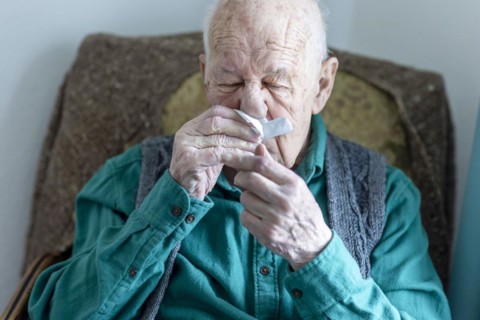 Old man blowing his nose