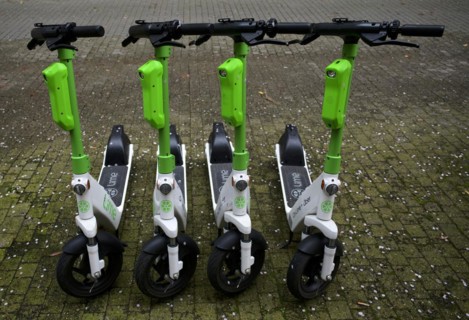 Four parked e-scooters in the bike rental of the company Lime