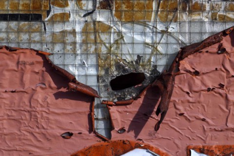 Peeling paint and hole in a glass pane secured with metal wire