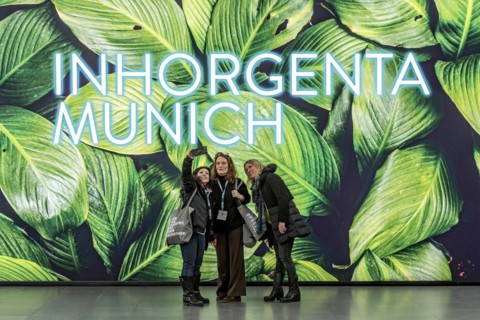 Young woman take a selfie in front of Inhorgenta Munich on LED display with tropical leaves