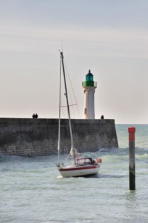 Lighthouse and sailing boat entering the harbour of Saint-Valery-en-Caux