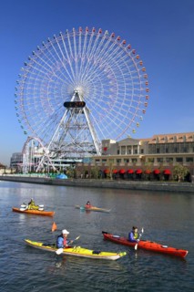 Group of kayaks on excursion and Ferris Wheel Cosmo Clock 21 of Yokohama Cosmo World in background Yokohama city Kanagawa Japan
