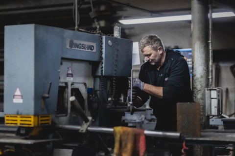 A metal worker clamps a piece of metal into a machine