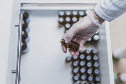 A prescription worker takes a dropper bottle from a drawer