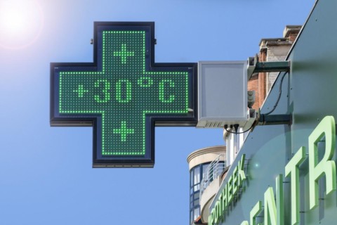 Thermometer in green pharmacy screen sign displays extremely hot temperature of 30 degrees Celsius during heatwave