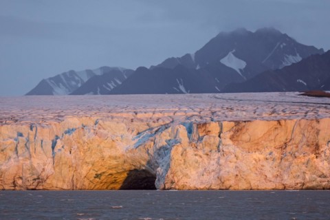 Entrance of giant ice cave at sunset in the Kongsbreen glacier calving into Kongsfjorden