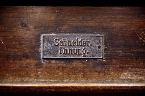 Permanently mounted sign of the tailors' guild on the church pew in the Nikolaikirche