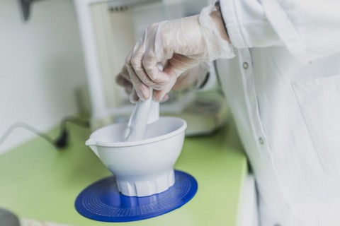A prescription employee mixes an olive ointment in a fan bowl