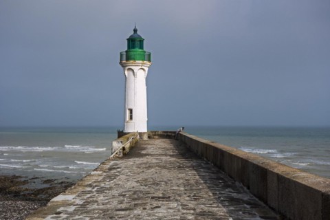 Lighthouse and lonely man looking at sea from pier in the harbour at Saint-Valery-en-Caux