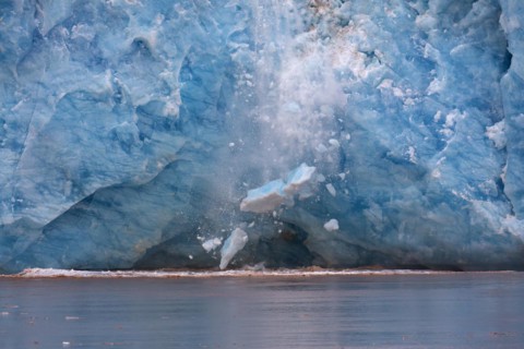 Huge ice chunk breaking from the edge of the Kongsbreen glacier calving into Kongsfjorden