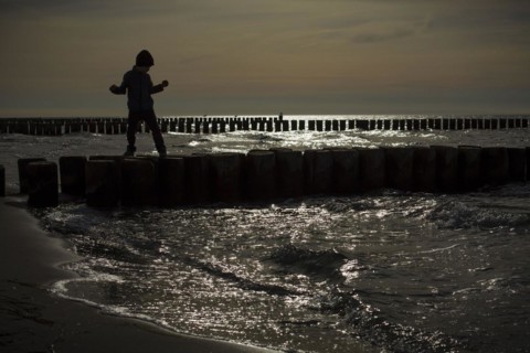 Symbolic photo on the subject of children's fear. A child balances on wooden stilts over the water. Arenshoop