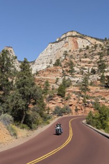 Motorcyclist riding a Harley Davidson without helmet on the panoramic Zion-Mt.Carmel Highway through bizarre rocky landscape