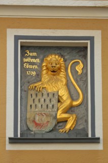 Golden lion figure with coat of arms and inscription Gasthaus zum goldenen Loewen and year 1709