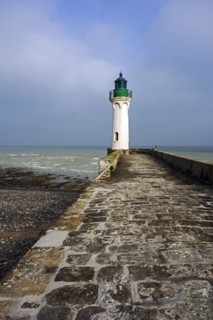 Lighthouse and lonely man looking at sea from pier in the harbour at Saint-Valery-en-Caux