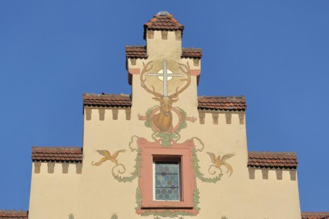 Stepped gable of the historic Deer Pharmacy with mural and stag figure with cross and sun