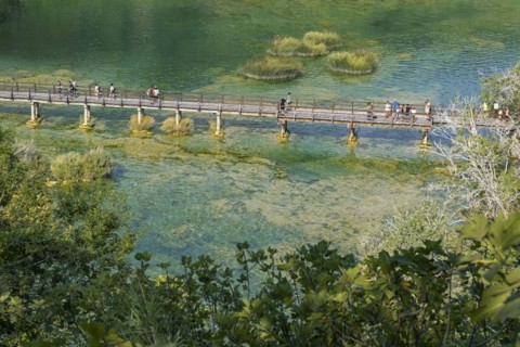 Tourists walking over wooden footbridge over pond in Skradinski buk at the Krka National Park near