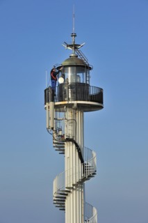 Worker wearing safety harness doing maintenance work on the Alprech lighthouse with spiralling exterior staircase near Le Portel