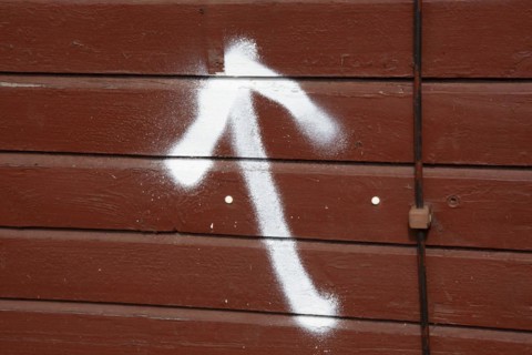 A spray-painted white arrow on a board wall points upwards