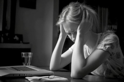 Young woman sitting exhausted at a notebook