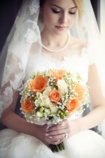 A bride in a white wedding dress holds a beautiful bridal bouquet