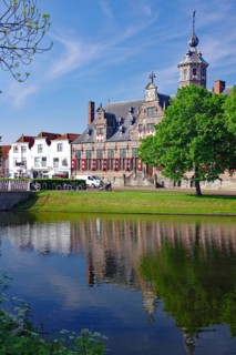 The former town hall reflected in the water of a canal