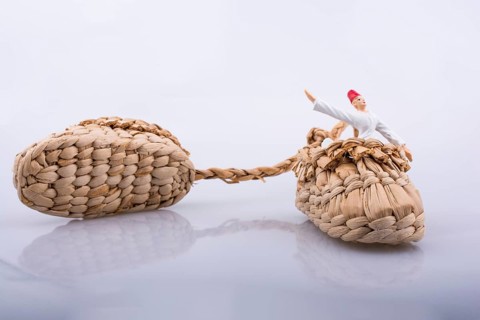 Whirling dervish riding in a straw shoe on a white background