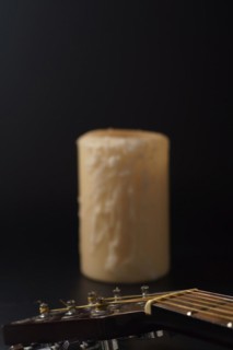 Spanish guitar neck with a candle in the background on a black background