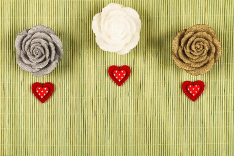 3 decorative roses with 3 small red hearts on a green background