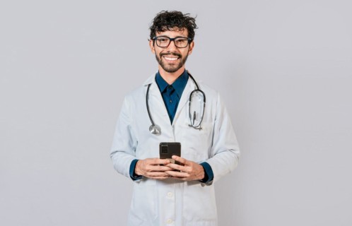 Happy doctor with phone on isolated background. Smiling doctor using cellphone isolated