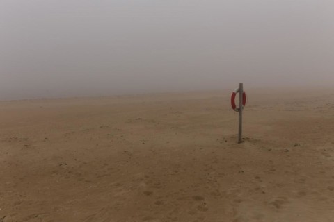 Lifebelt hanging from a post on the beach at Nebel