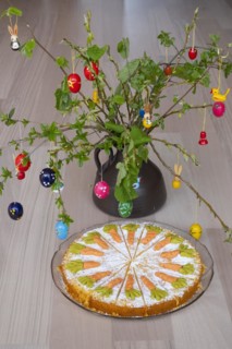 Homemade carrot cake in front of a shrub with Easter decorations