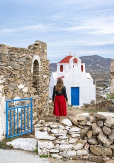 Young woman with red skirt at the entrance gate with ruined wall