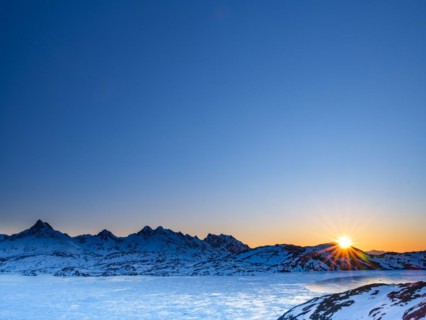 Sunrise over snowy mountains above the frozen Kong Oscar Fjord
