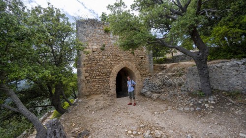 Hikers in front of the tower of the castle ruins Castell Alaro