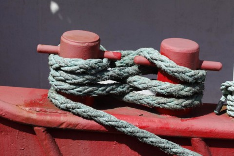 Red ship's bollard wrapped with ship's rope