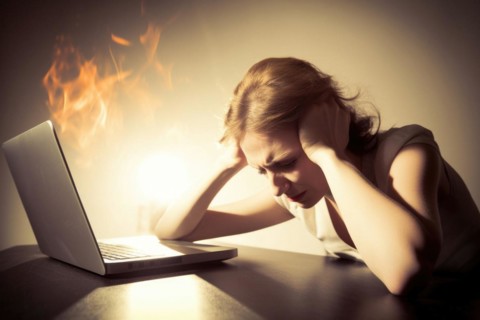Young woman sitting exhausted at a notebook