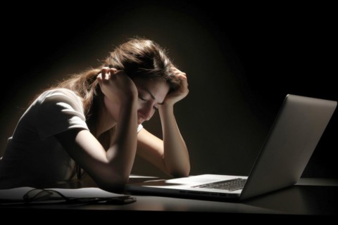 Young woman sitting exhausted at a notebook