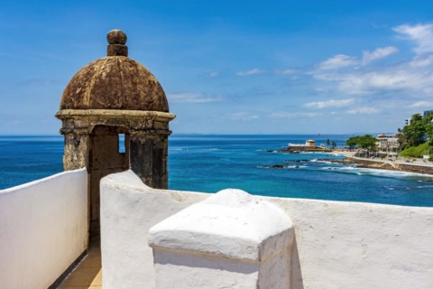 Wall and guardhouse of an old historic fort on the edge of the city of Salvador in Bahia with the sea and the city in the background