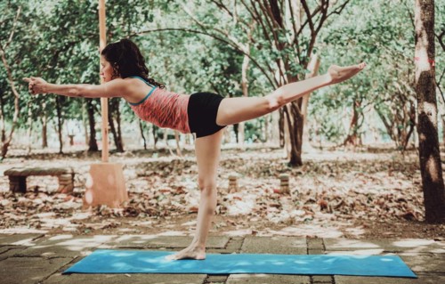 Young woman doing yoga pose warrior III. Spiritual girl practicing yoga Virabhadrasana III outdoors