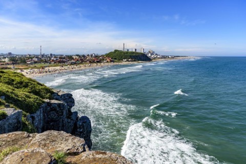 Crowded beach and rocks on a beautiful sunny day in the summer of Torres city on the coast of Rio Grande do Sul state