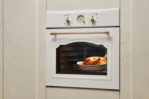 Process of baking food in oven. Whole chicken in ceramic casserole inside the oven
