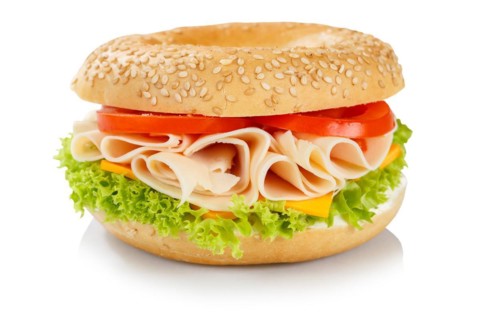 Bagel sandwich for breakfast topped with chicken and ham in front of a white background in Stuttgart