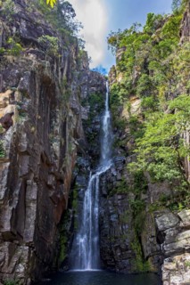 Stunning waterfall called Veu da Noiva between moss covered rocks and the vegetation of an area with nature preserved in the state of Minas Gerais