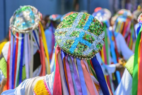 Men dressed in colorful clothes and hats attending a popular religious festival in Minas Gerais