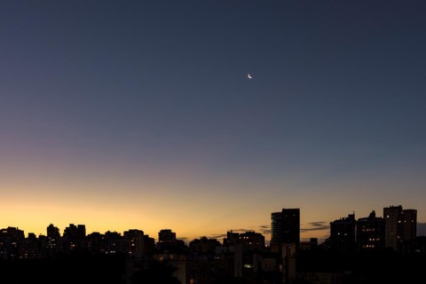 Skyline of Porto Alegre at dusk with the moon in the sky with buildings silhuette